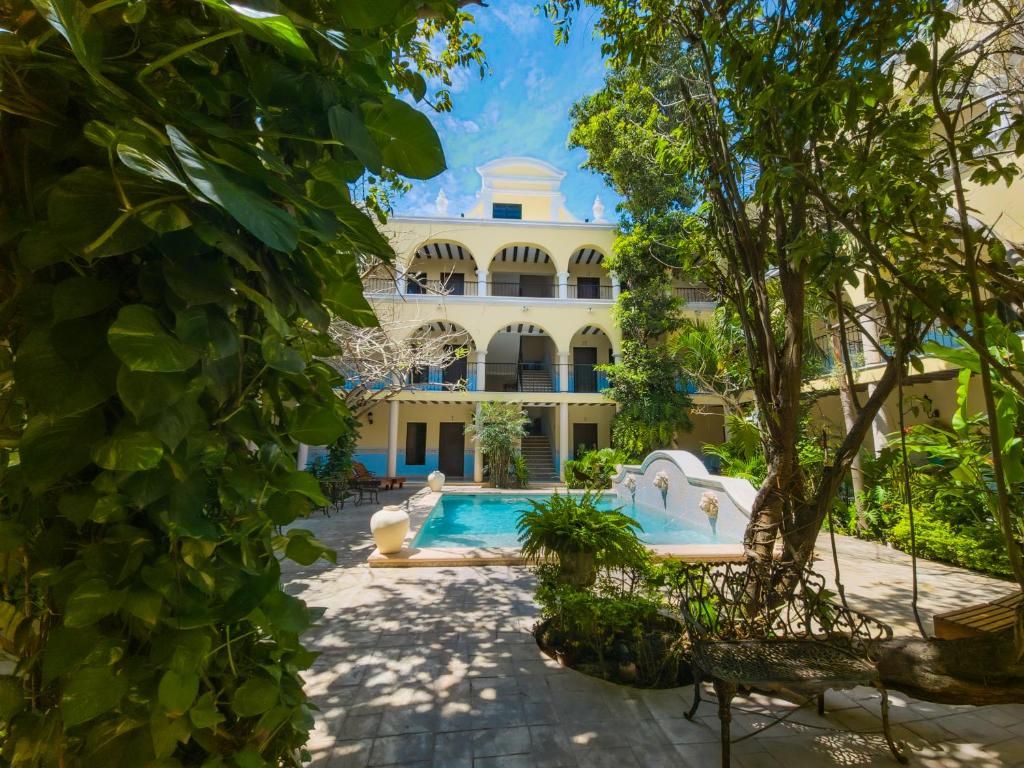 A courtyard with a pool, surrounded by lush greenery and a building with arches.