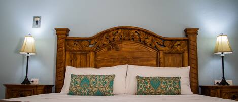 A neatly made bed with a wooden headboard, two bedside lamps, and decorative pillows.