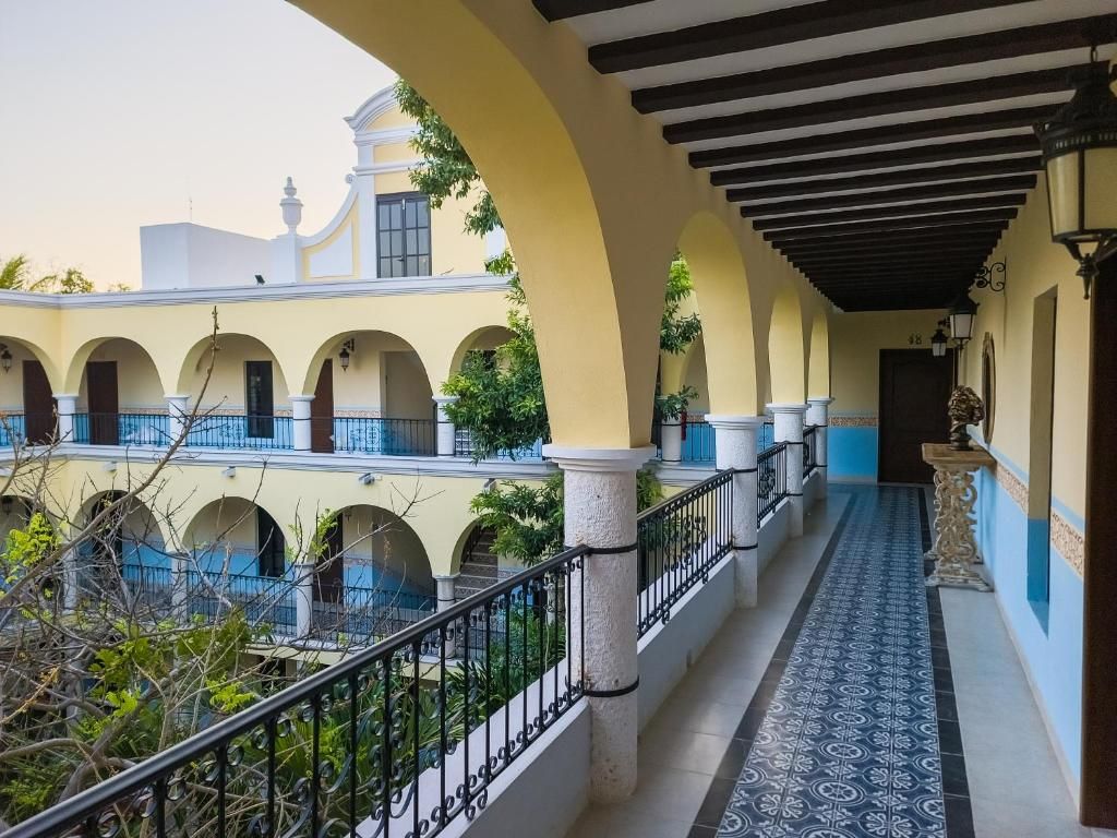A covered corridor with arches, a tiled floor, and a view of a building with balconies.