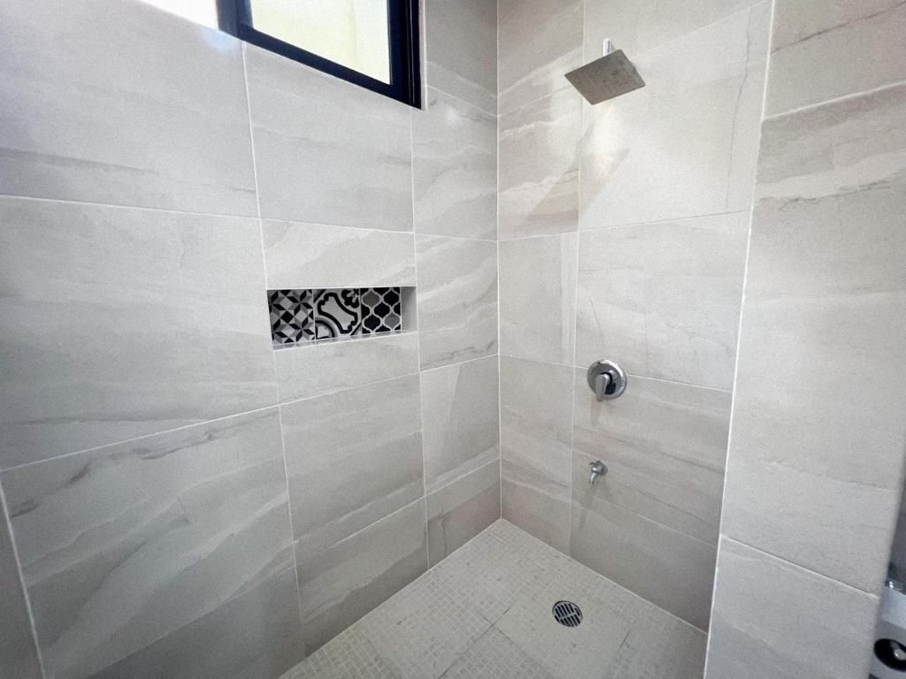 A small, enclosed shower area with a drain, a window, and a showerhead.