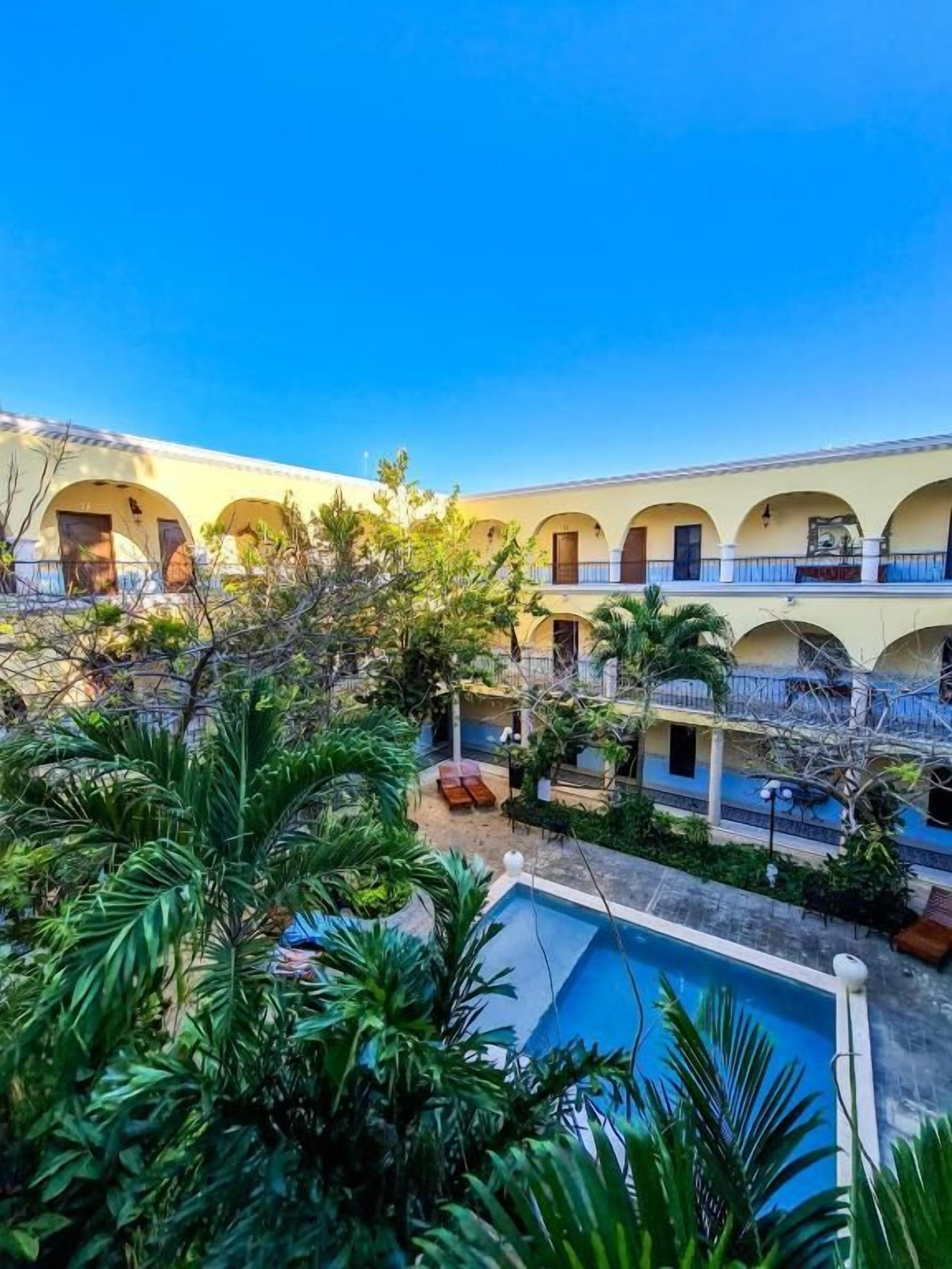 A courtyard with a pool, surrounded by greenery and buildings with arches.