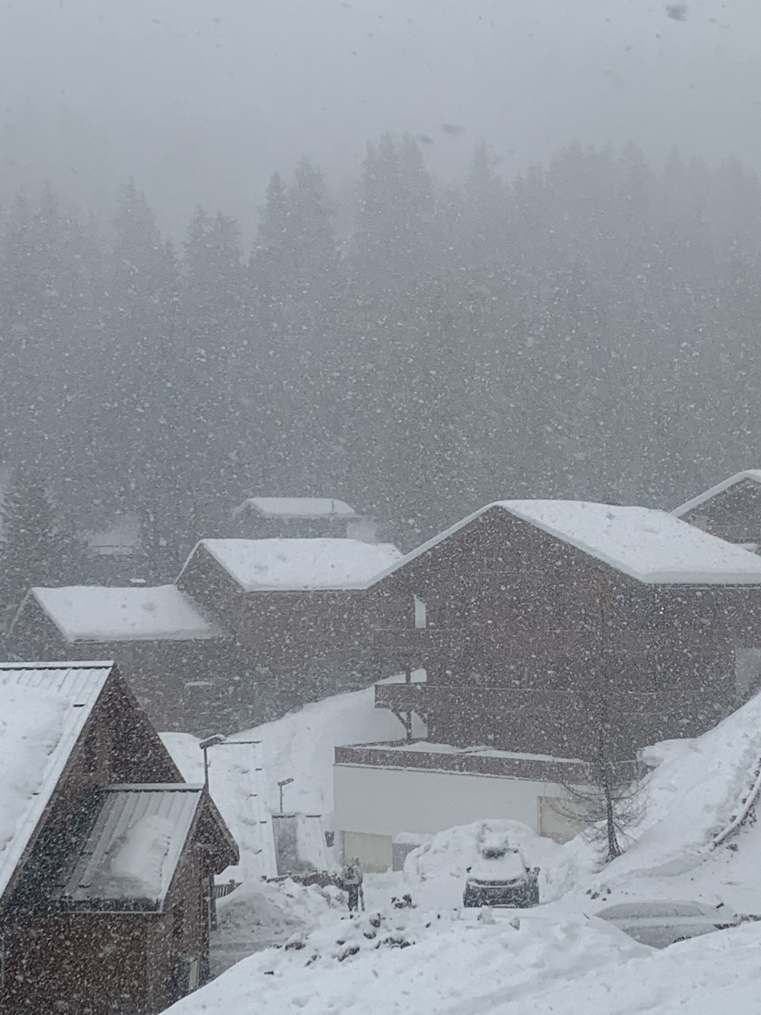 Een besneeuwd dorp met traditionele huizen, een kerk en een kleine weg.