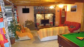 Un salón acogedor con mesa de billar, chimenea y pared de piedra.