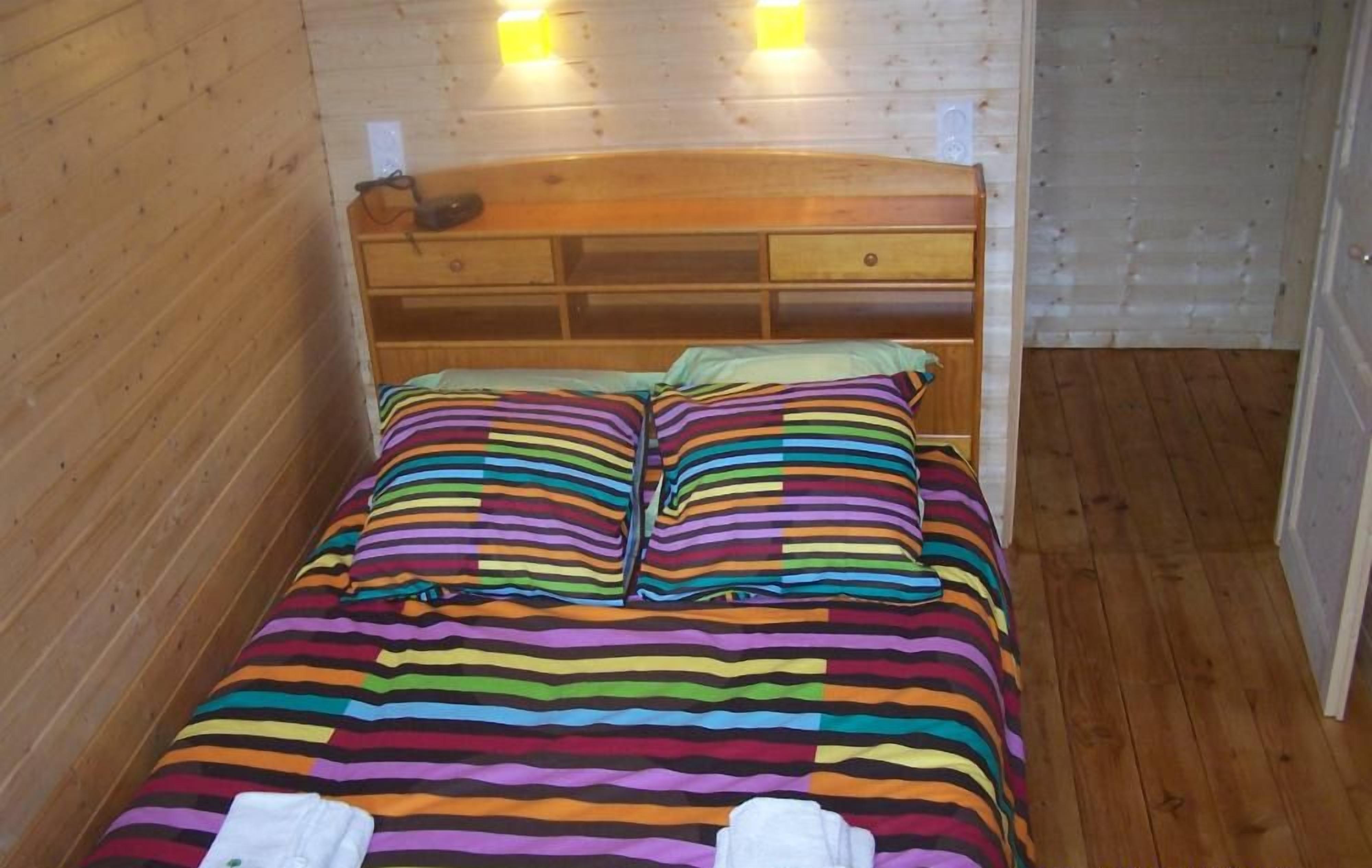 A wooden bed with striped bedding and two folded towels.