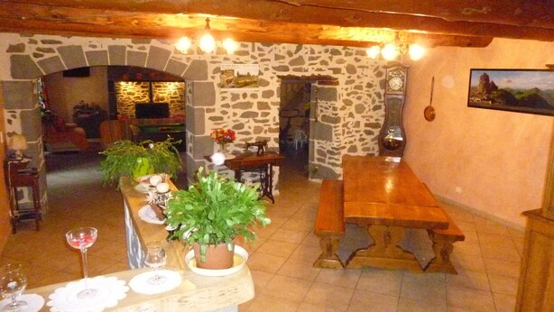 Un interior rústico con pared de piedra, techo de madera y un comedor con banco y mesa.