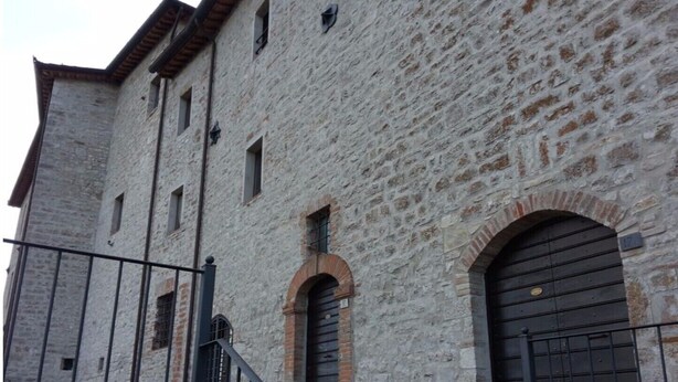 A stone building with a metal gate, arched windows, and a large door. - Castello Izzalini Todi Resort "Apt 4" (Izzalini)