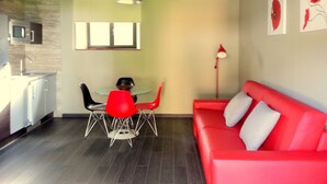 A modern kitchen with a dining area, a red sofa, and artwork on the walls. - Rural apartment Casona la Sierra for 4 people (Cudillero)