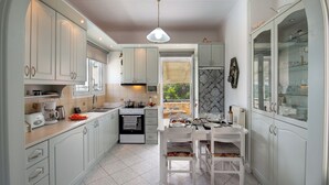 A modern kitchen with white cabinets, a dining area with a table and chairs, and a view of the outdoors through a window.