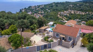 A residential area with a house featuring a tiled roof, a swimming pool, and a garden.