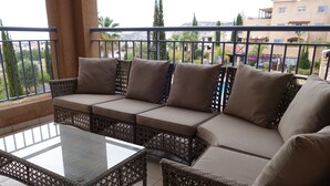 A balcony with wicker furniture, including a sofa and a table. - Luxury Aptmt, Seaview Sunset, Large Pool, free Wi-Fi, UK-TV (Peyia)
