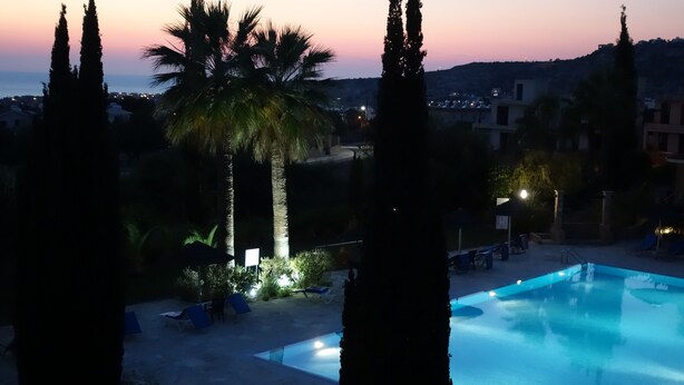 A swimming pool with lounge chairs and palm trees at dusk. - Luxury Aptmt, Seaview Sunset, Large Pool, free Wi-Fi, UK-TV (Peyia)