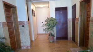 A hallway with a potted plant, wooden doors, and a marble floor. - Apartment in Tangier, by the sea with swimming pool and garage. (Tanger)
