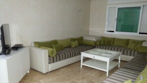 A living room with a sofa, a coffee table, and a television. - Apartment in Tangier, by the sea with swimming pool and garage. (Tanger)