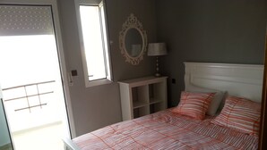 A bedroom with a bed, a window, a mirror, and a lamp. - Apartment in Tangier, by the sea with swimming pool and garage. (Tanger)