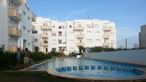 A swimming pool surrounded by a grassy area with a multi-story building in the background. - Apartment in Tangier, by the sea with swimming pool and garage. (Tanger)
