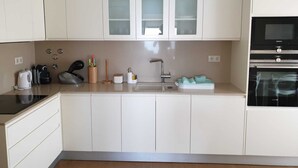 Een moderne keuken met witte kastjes, een roestvrijstalen spoelbak, een zwarte magnetron en een inbouwoven.