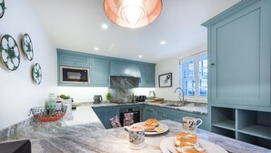 Una cucina moderna con mobili color petrolio, un piano di lavoro in marmo e un'ampia finestra.