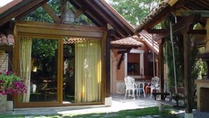 Una casa de madera con puerta de vidrio y un patio con mobiliario exterior.