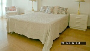 Una camera da letto con un letto grande, due comodini con lampade, una sedia e un quadro floreale appeso al muro.