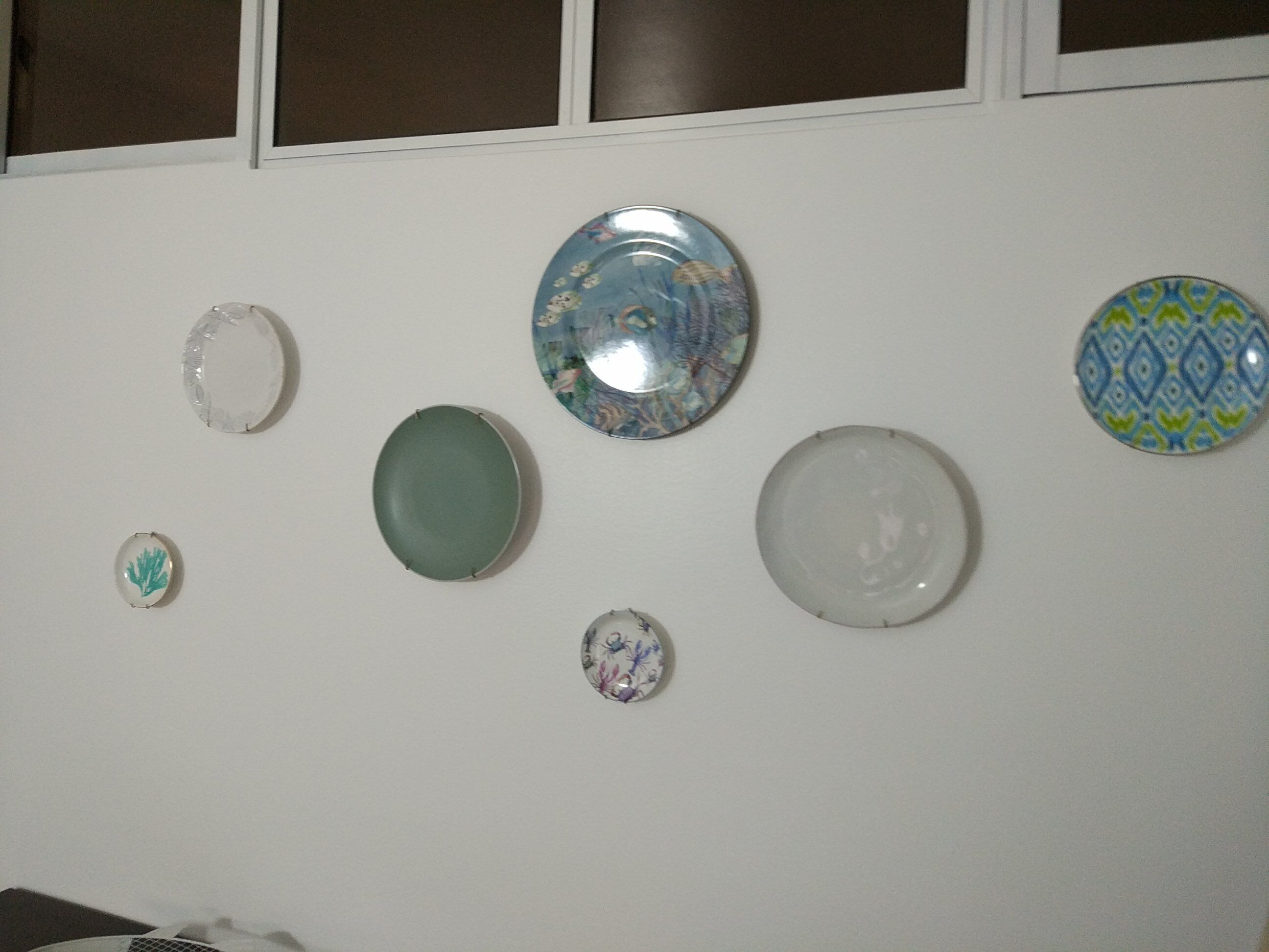 Una pared con siete platos decorativos de diversas formas y diseños.