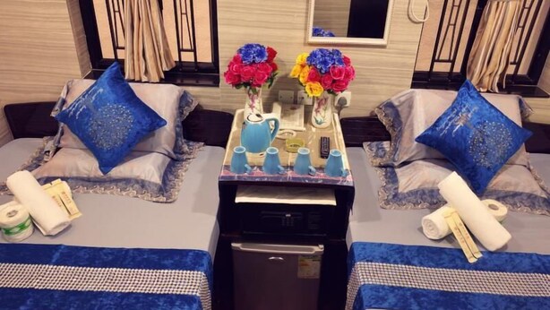A hotel room with two beds, a small table with a vase of flowers, a printer, and a minibar. - Pacific Lodge (Kowloon)