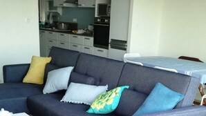A modern living room with a grey sofa, a small white table, and a blue patterned rug.