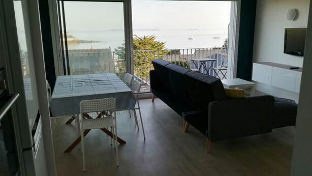 A balcony with a table and chairs, a sofa, and a TV on the wall.