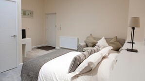 Une chambre à coucher comprenant un lit, une table de chevet, une lampe et une porte donnant sur une autre pièce.