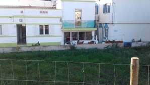 Un edificio residencial con balcón, una puerta y una ventana con persianas.
