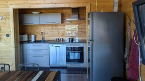 A modern kitchen with wooden walls, stainless steel appliances, and a dining area with a wooden table and chairs. - L' Edelweiss, luxury chalet with exceptional lake view, close to center/slopes (Gérardmer)