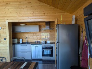 Una cucina moderna con pareti in legno, elettrodomestici in acciaio inossidabile e un'area pranzo con tavolo e sedie in legno.