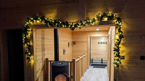 A hallway with a wood-burning stove, wooden walls, and a garland of lights. - L' Edelweiss, luxury chalet with exceptional lake view, close to center/slopes (Gérardmer)