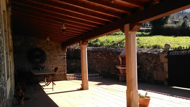 Une terrasse extérieure dotée d’un plafond en bois, de murs en pierre et d’un sol en pierre.