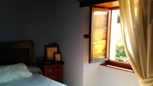 Une chambre à coucher avec un lit, une table de chevet avec une lampe et une fenêtre avec des rideaux.