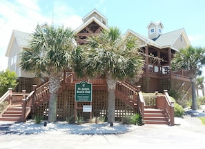 A two-story building with a wooden deck and stairs, surrounded by palm trees. A sign indicates it is the St. James Beach Club, private property, and no pets are allowed.