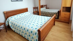 Un dormitorio con una cama de madera, un armario de madera, una silla y una mesita.
