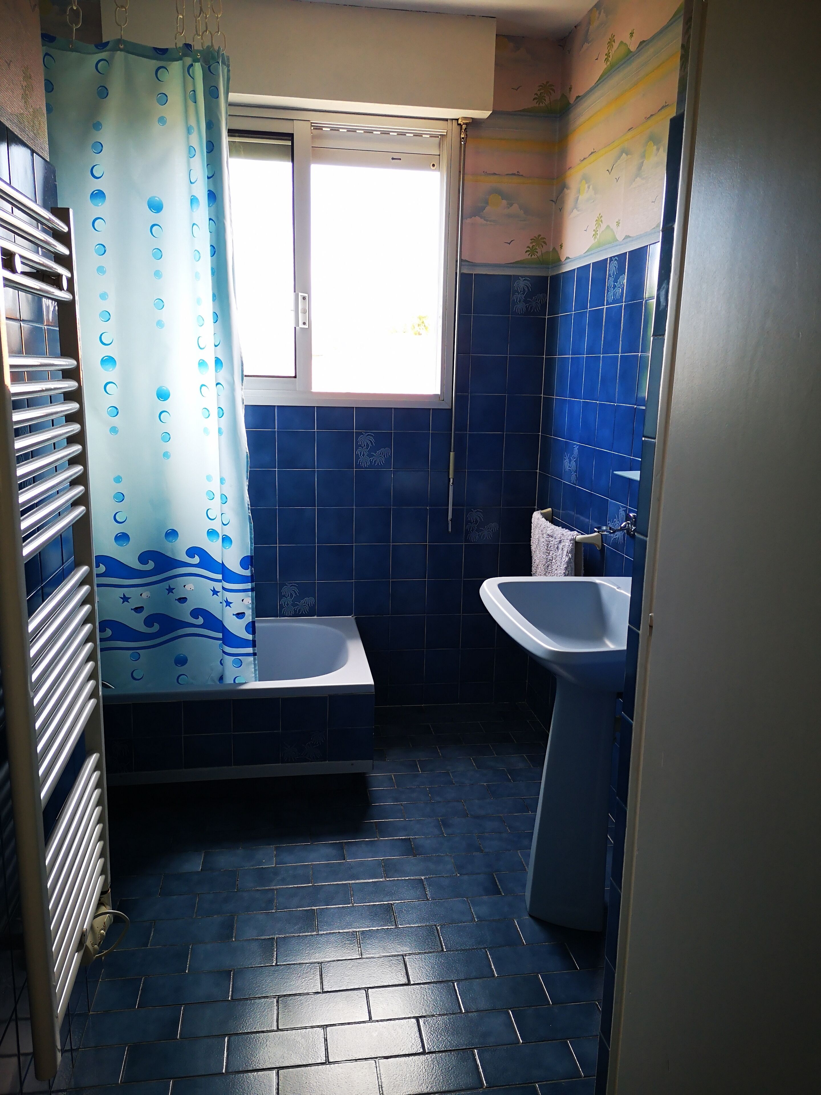 Een badkamer met een bad, een wastafel en een raam.