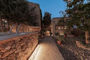 A stone pathway leading to a building with a metal railing and potted plants. - San Pedro Rural Apartments (2 pax) in Valencia de Alcántara  (Valencia de Alcántara)