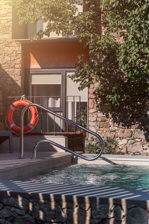 A pool with a metal ladder, a lifebuoy, and a stone wall. - San Pedro Rural Apartments (2 pax) in Valencia de Alcántara  (Valencia de Alcántara)