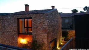 A stone building with a window and a lit interior, suggesting a cozy interior.