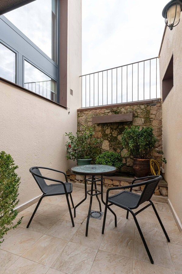 A small outdoor patio with a round table and two chairs, a stone wall, and potted plants. - San Pedro Rural Apartments (2 pax) in Valencia de Alcántara (Valencia de Alcántara)