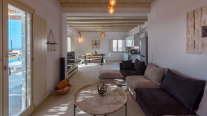 A spacious living area with a sofa, a coffee table, and a view of a pool through a sliding door. - Cycladic Breeze Villa Aura with swimming pool villa & great sea view  (Paros)