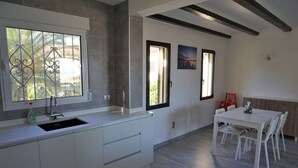Eine moderne Küche mit großem Fenster, einer Spüle und einem Essbereich mit Tisch und Stühlen.