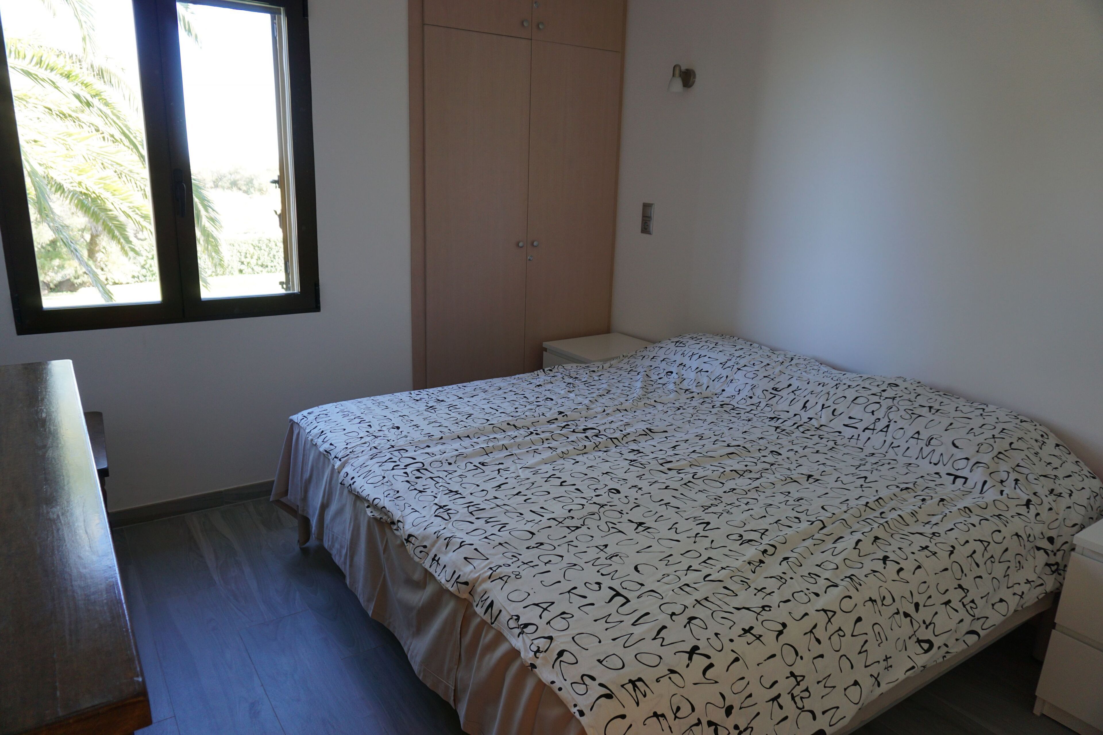 A bedroom with a bed, a wardrobe, a window, and a desk.