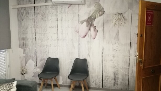 Ett rum med två svarta stolar, en trädörr och en vägg med blommig tapet.
