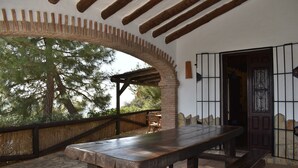 An outdoor patio with a wooden bench and table, a brick archway, and a door with metal bars. - Finca Almencino with private pool for 6 people, fantastic sea views (Cómpeta)