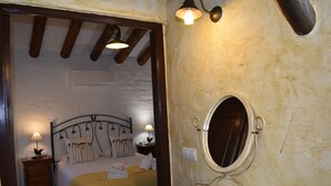 A bedroom with a bed, bedside table, lamp, and a bathroom with a sink and mirror. - Finca Almencino with private pool for 6 people, fantastic sea views (Cómpeta)