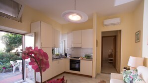 A modern kitchen with white cabinets, a built-in oven, and a dining area with a table and chairs. - Vietri center "Villa Anna" (Vietri Sul Mare)