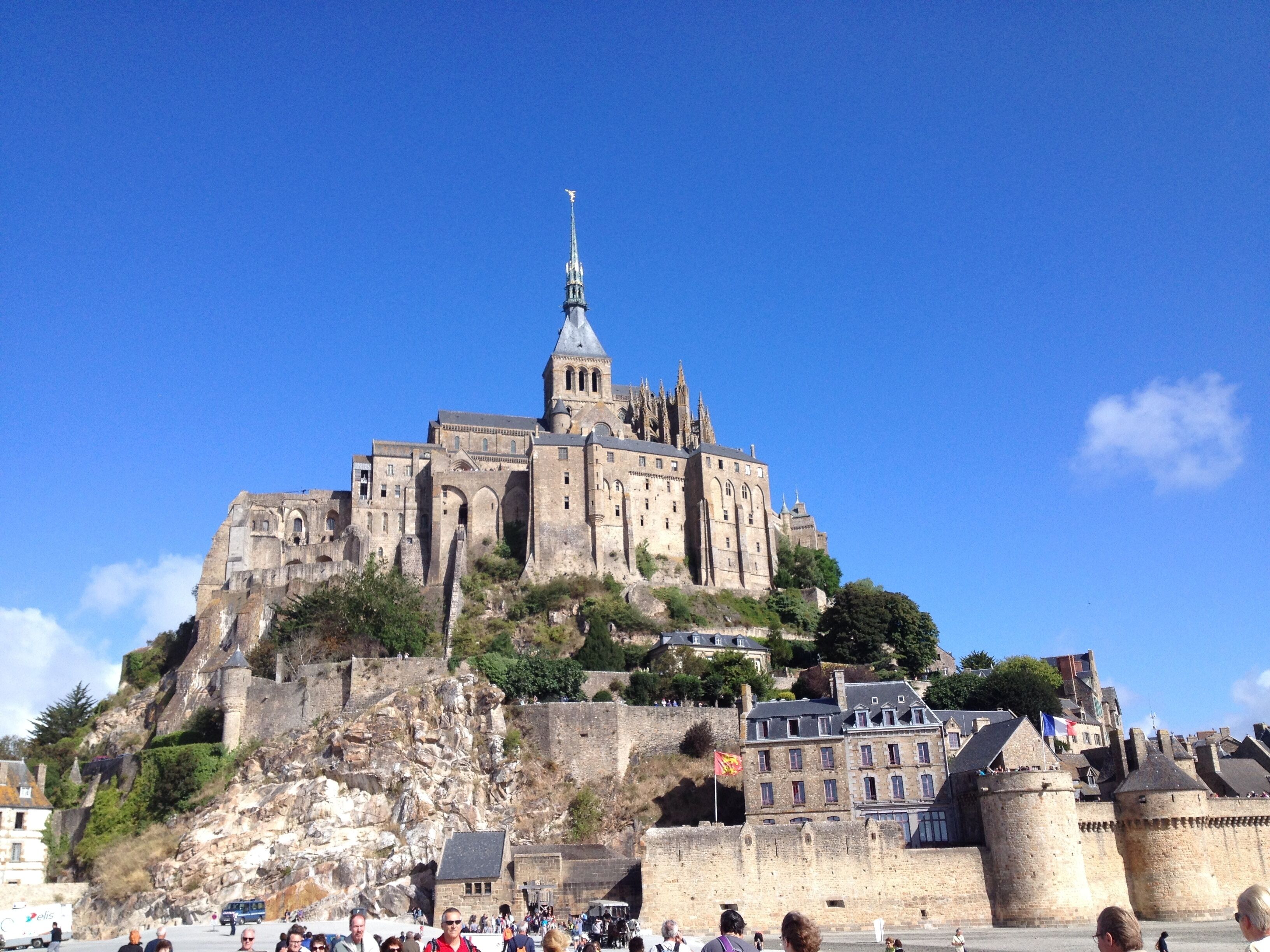 A historic castle with a prominent tower, situated on a hill with a clear blue sky.