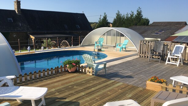 A swimming pool with lounge chairs and a covered seating area.